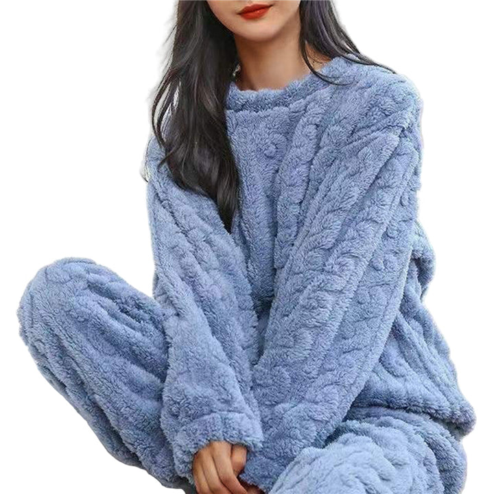 Vrouw in blauwe fleece pyjamaset met gedraaid reliëfpatroon, zittend op een witte achtergrond 1