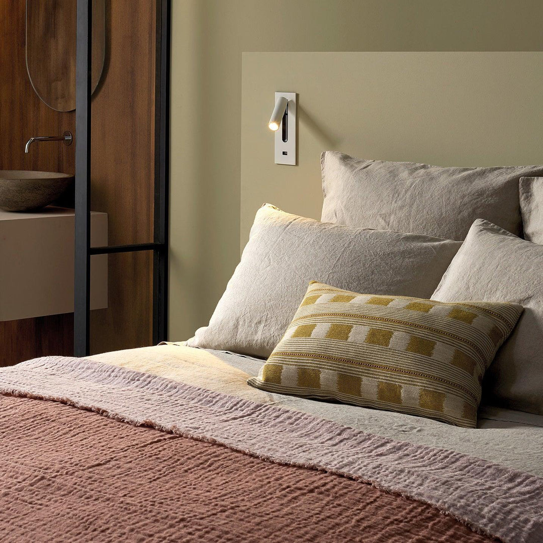 Witte wandlamp met usb-aansluiting boven een bed met linnen kussens en groene wand 31