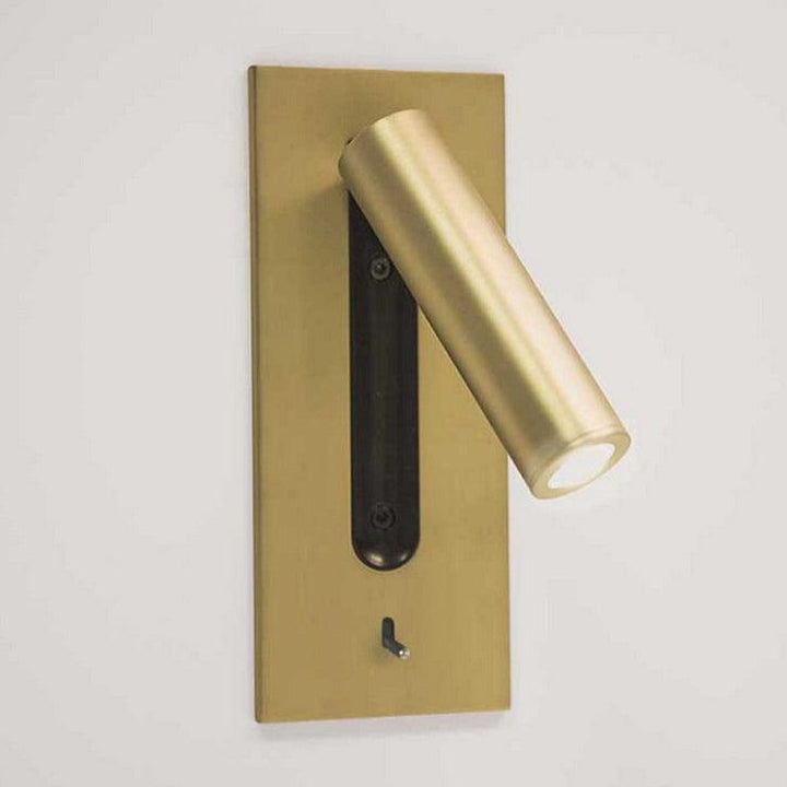 Goudkleurige wandlamp met naar rechts gedraaide ledspot en zwarte uitsparing, tegen een lichte muur 26