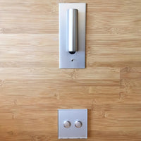 Zilverkleurige wandlamp met rechtopstaande spot in een bamboe wand, met dubbele schakelaar eronder 34