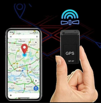 Hand houdt de kleine zwarte tracker vast naast een smartphone met een kaart en rode locatiemarkering op donkere achtergrond. 7