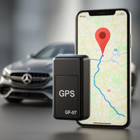Zwarte mini-tracker op de voorgrond, met op de achtergrond een smartphone met een kaart en route en een auto. 1