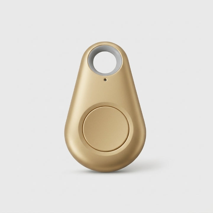 Goudkleurige druppelvormige tracker met ronde knop en grijs sleutelring-gat op een lichte achtergrond 11