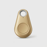 Goudkleurige druppelvormige tracker met ronde knop en grijs sleutelring-gat op een lichte achtergrond 11