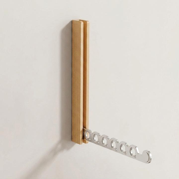 Lichthouten wandkapstok met uitgeklapte zilverkleurige metalen arm met zes ronde gaten, schuin van opzij gezien tegen een lichte muur. 9
