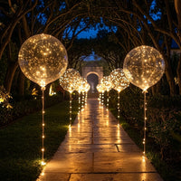 Lichtgevende transparante ballonnen langs een verlicht tuinpad in de avond, met een poort op de achtergrond 1