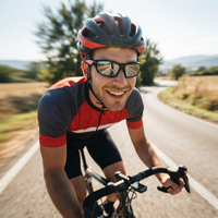 Lachende wielrenner met helm draagt de sportzonnebril tijdens het fietsen op een zonnige landweg 2