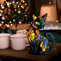 De kattenlamp op een tafel naast witte mokken, met een kerstboom met lichtjes erachter 4