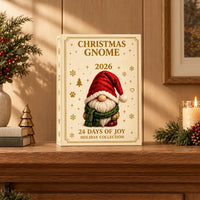 Crèmekleurige adventsdoos met goudkleurige details en een kabouter met rode muts en groene sjaal, op een houten schouw tussen kerstdecoratie en een brandende ka 1