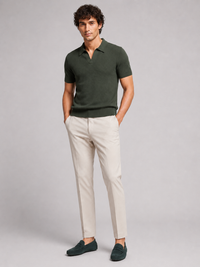 Donkergroen poloshirt in volledig model van voren, met crèmekleurige broek en donkergroene suède loafers 13