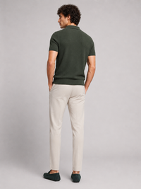 Achterkant van het donkergroene poloshirt, model kijkt opzij, met crèmekleurige broek en groene loafers 14