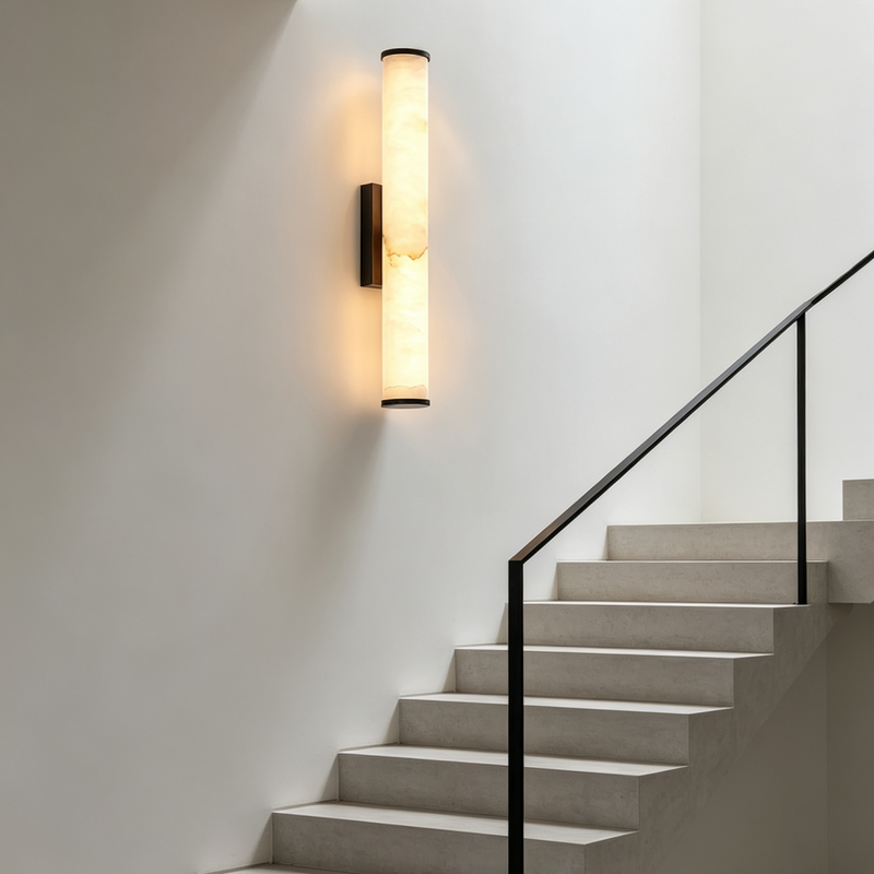 Verticale marmeren wandlamp op een witte trapmuur, naast een trap met zwarte leuning. 7