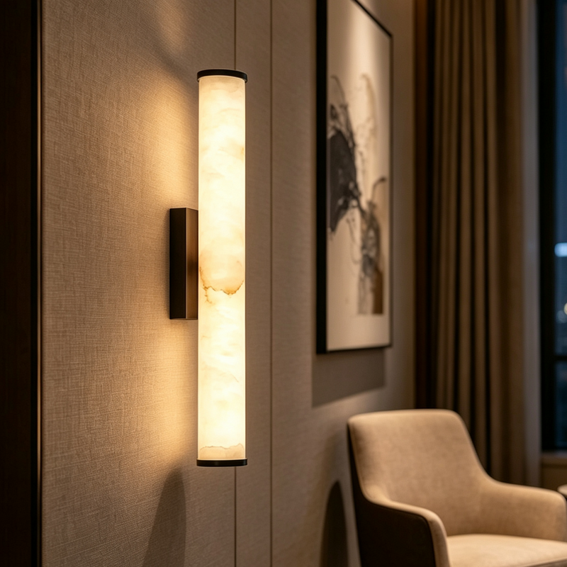 Close-up van een warm brandende marmeren wandlamp op een geweven wandbekleding, naast een ingelijst schilderij en een beige stoel. 12