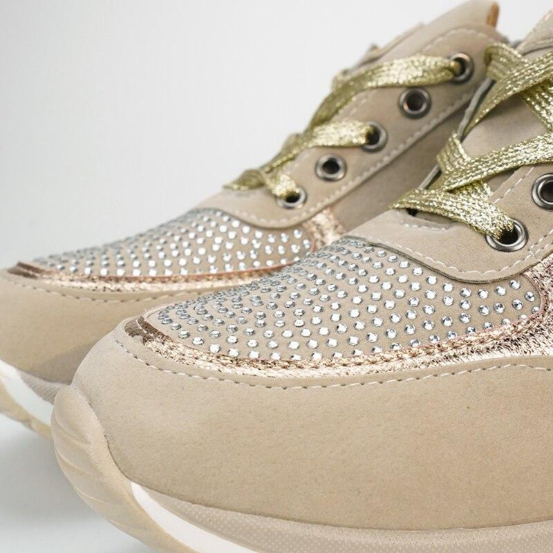Close-up van de neus van twee beige sneakers met strassteentjes, gouden metallic veters en een witte zool. 10