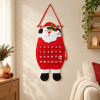 Vilten kerstmankalender met 24 vakjes hangt aan een crèmekleurige muur in een gezellige woonkamer met kerstversiering, een plant en een bank. 1