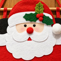 Close-up van het gezicht van de vilten kerstman met witte baard, rode pompomneus, hulstblaadjes met bessen en een houten ophangstok. 3
