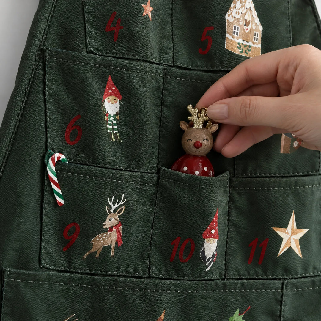 Close-up van de stoffen vakjes met genummerde kerstprintjes, waaruit een hand een klein rendiertje pakt. 3