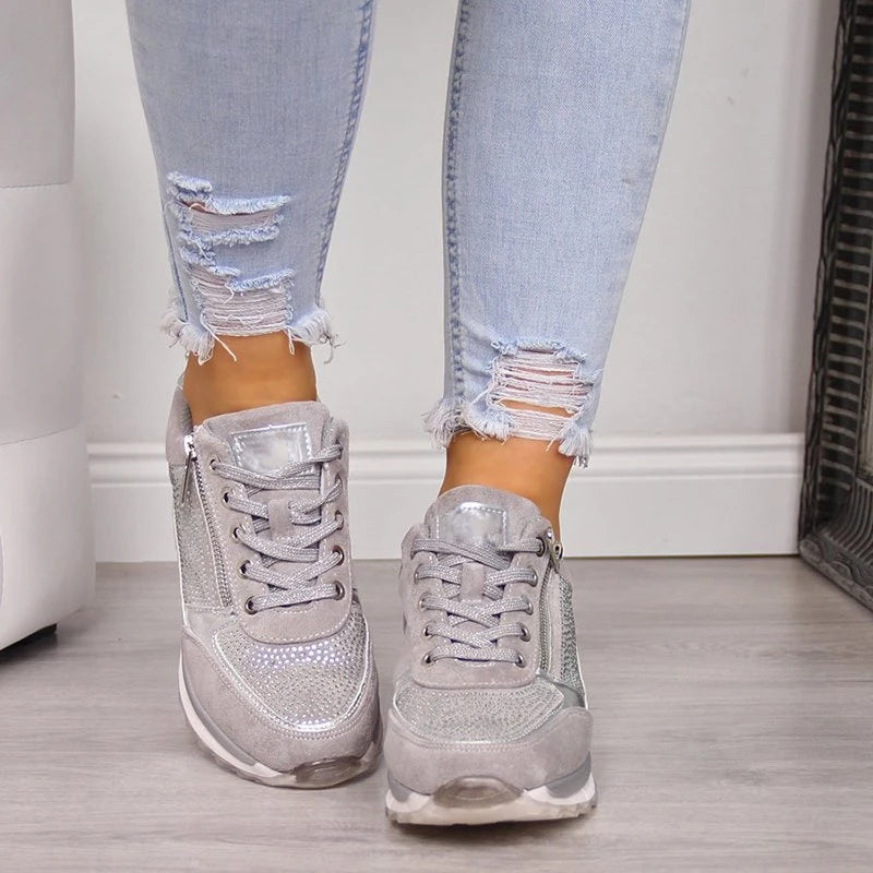 Vooraanzicht van grijze gevlochten sneakers met strassteentjes, zijrits en veters, gedragen met een gescheurde spijkerbroek. 5