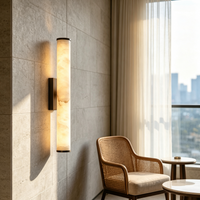 Gloeiende marmeren wandlamp op een stenen wandbekleding, naast een rieten fauteuil en een raam met gordijn en uitzicht op de stad. 8