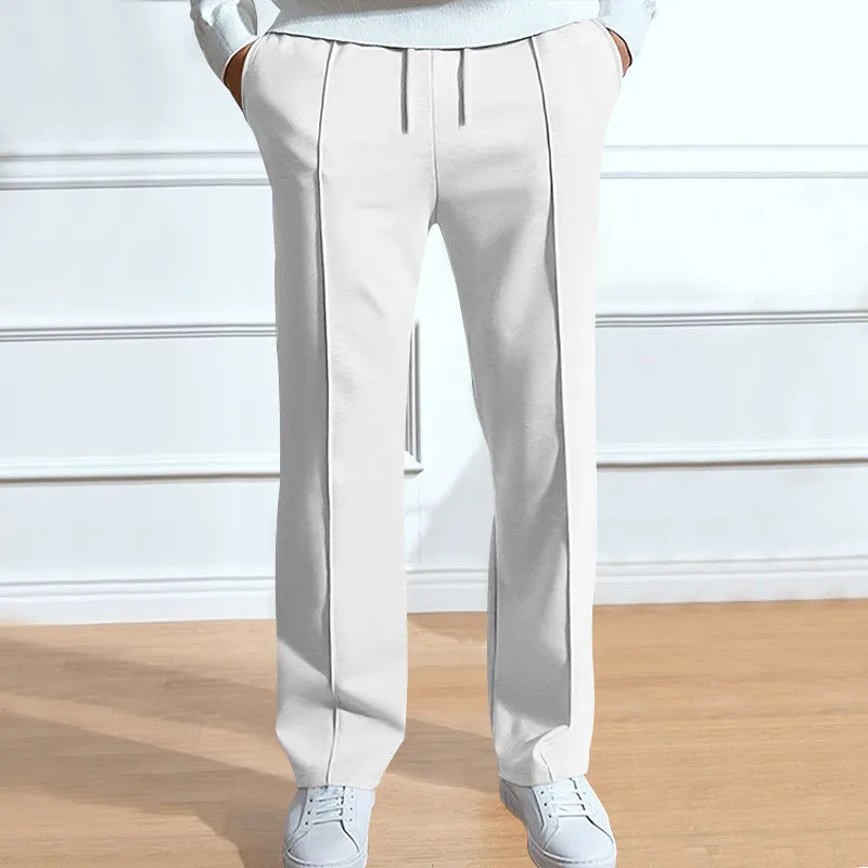 Witte broek met trekkoord en persvouw aan de voorkant, gedragen met witte sneakers en een lichte trui. 4