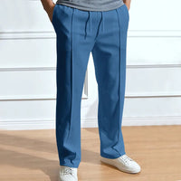 Blauwe broek met trekkoord en persvouw, gedragen door een model met witte sneakers en een grijs shirt. 5