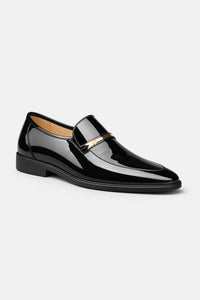 Zwarte glanzende lakleren loafer met gouden metalen bandje, schuin van voren gefotografeerd op witte achtergrond 1