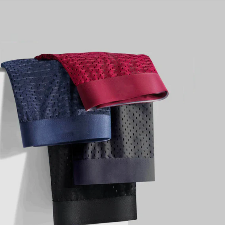 Drie gevouwen boxershorts in rood, blauw en zwart met geperforeerd gaasstof hangend over een rand 3