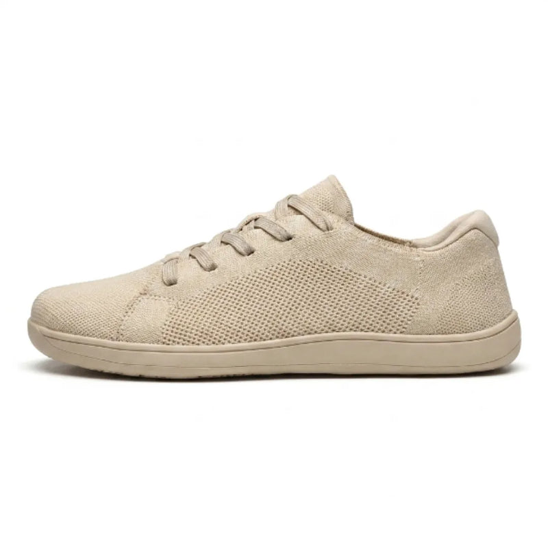 Beige gebreide sneaker van opzij gezien, met veters, ademende gaasvlakken en een effen beige zool op een witte achtergrond. 1