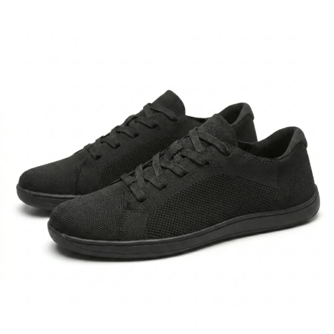 Paar zwarte gebreide sneakers schuin van voren, met veters en effen zwarte zolen op een witte achtergrond. 16