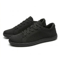 Paar zwarte gebreide sneakers schuin van voren, met veters en effen zwarte zolen op een witte achtergrond. 16