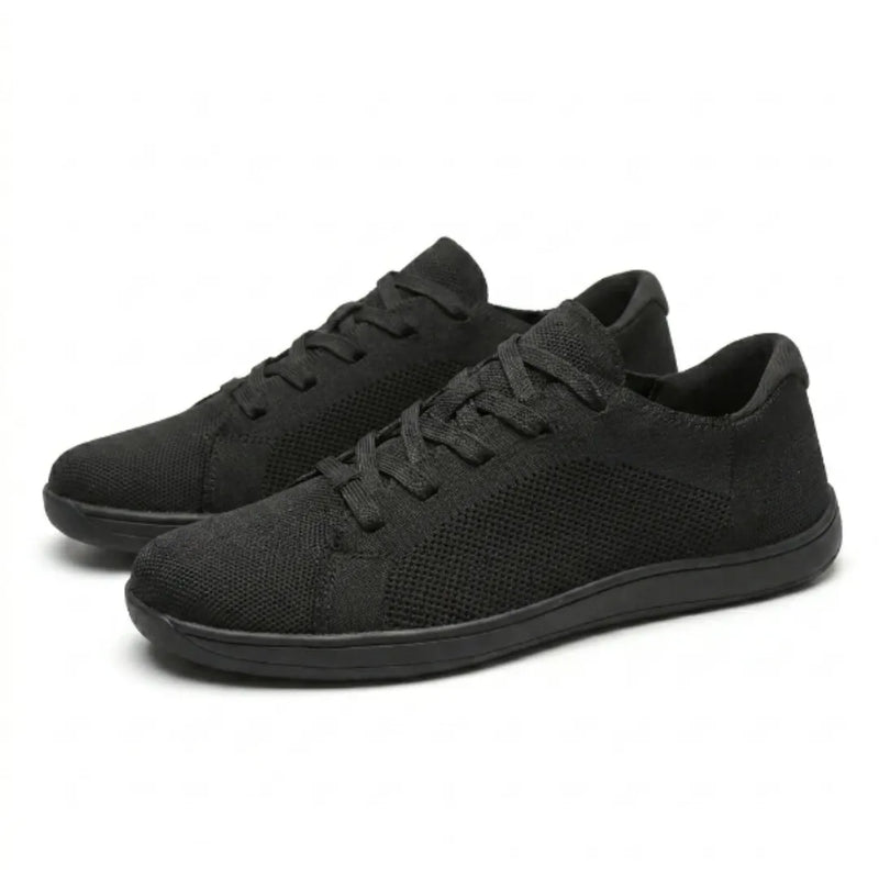 Paar zwarte gebreide sneakers schuin van voren, met veters en effen zwarte zolen op een witte achtergrond. 16
