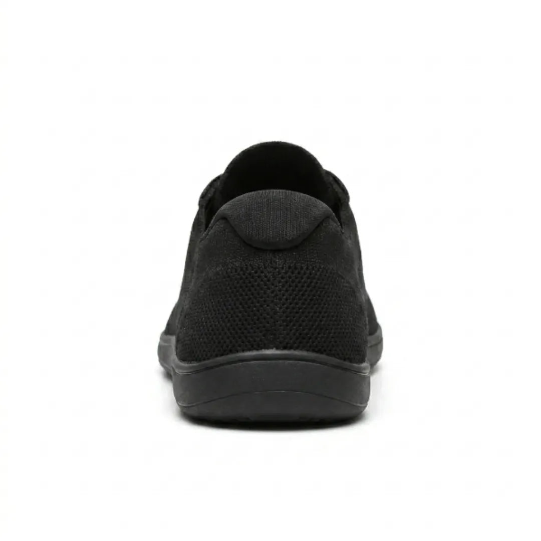 Zwarte gebreide sneaker van achteren, met het gaasdetail op de hiel en de brede, vlakke zool. 18