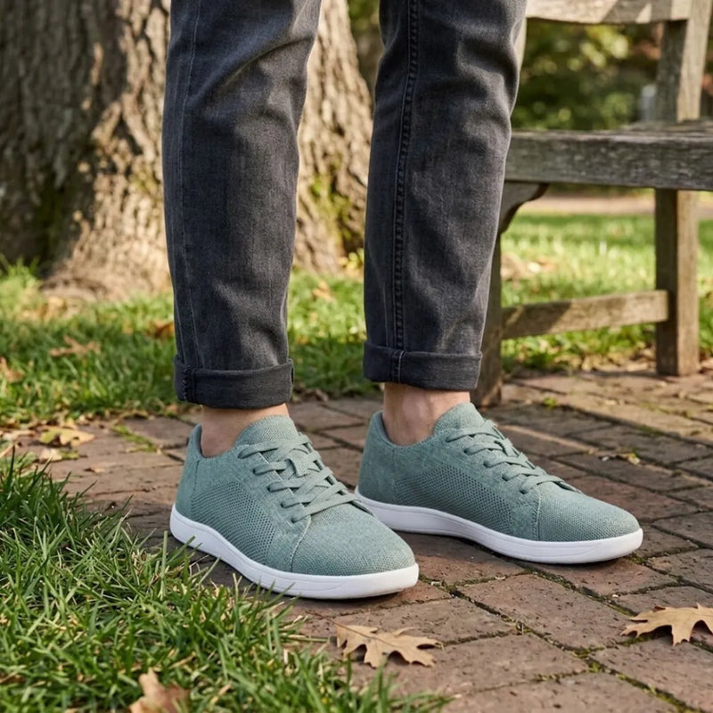 Model draagt de groene gebreide sneakers met witte zool op een stenen pad in het park, met opgerolde grijze spijkerbroek. 29