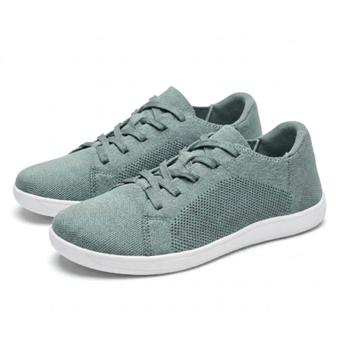 Paar groene gebreide sneakers met witte zool en veters, schuin van voren gezien op een lichte achtergrond. 34
