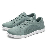 Paar groene gebreide sneakers met witte zool en veters, schuin van voren gezien op een lichte achtergrond. 34
