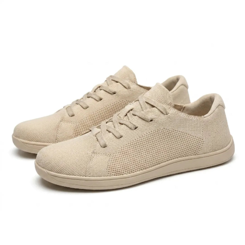 Paar beige gebreide sneakers schuin van voren, met veters en effen beige zolen op een witte achtergrond. 7