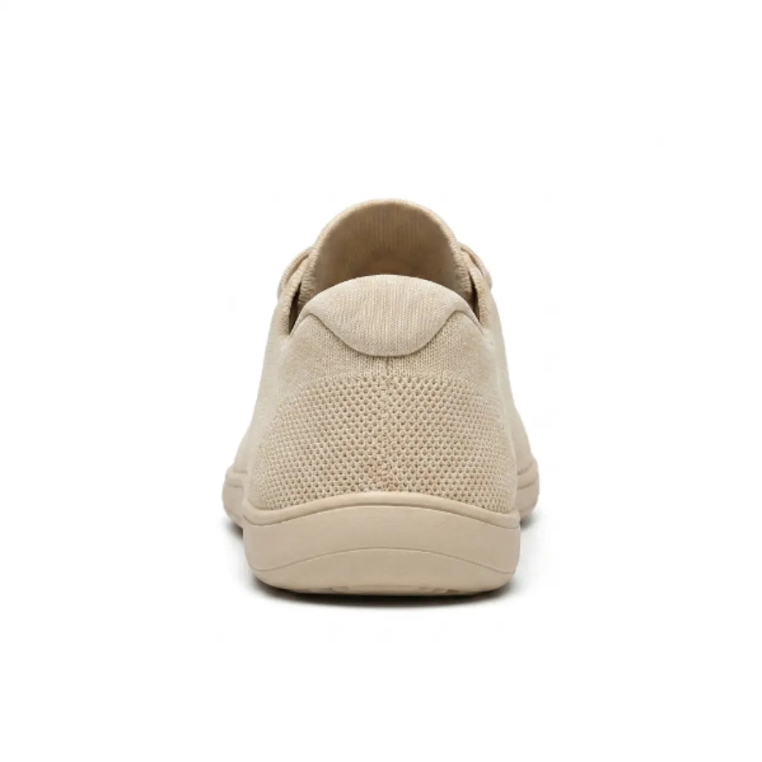 Beige gebreide sneaker van achteren, met het gaasdetail op de hiel en de brede, vlakke zool. 9