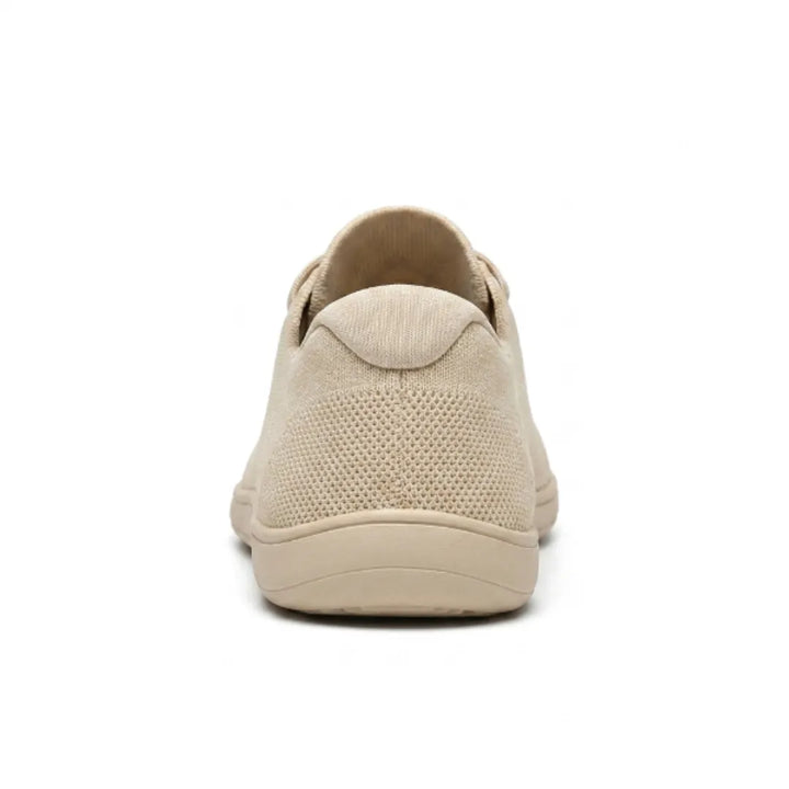 Beige gebreide sneaker van achteren, met het gaasdetail op de hiel en de brede, vlakke zool. 9