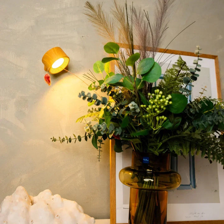 Wandlamp met houtlook behuizing verlicht een muur boven een boeket in een bruine vaas 5