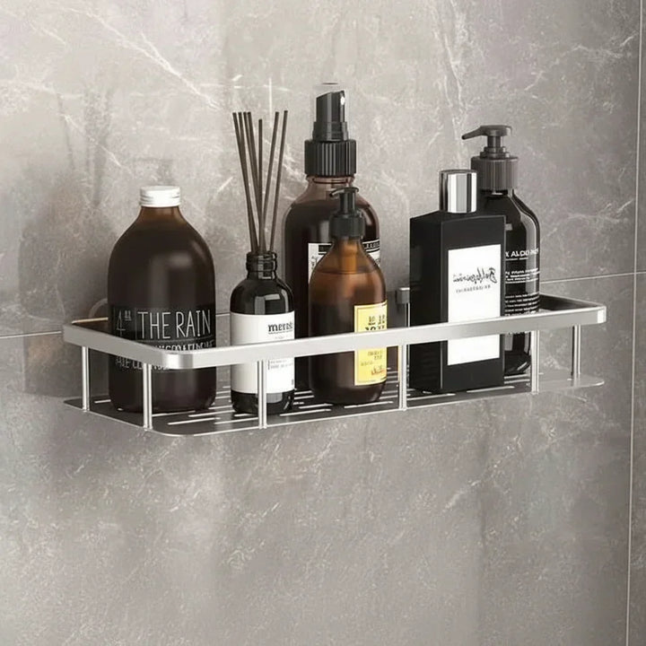 Zilverkleurige plank met geurstokjes en flessen op een grijze marmerlook wand 5