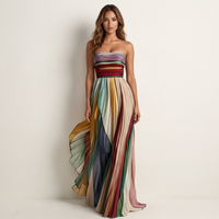 Vrouw in strapless maxi-jurk met gekleurde plooirok en gedrapeerd lijfje, vooraanzicht, terwijl de wijde rok aan één kant opwaait. 1