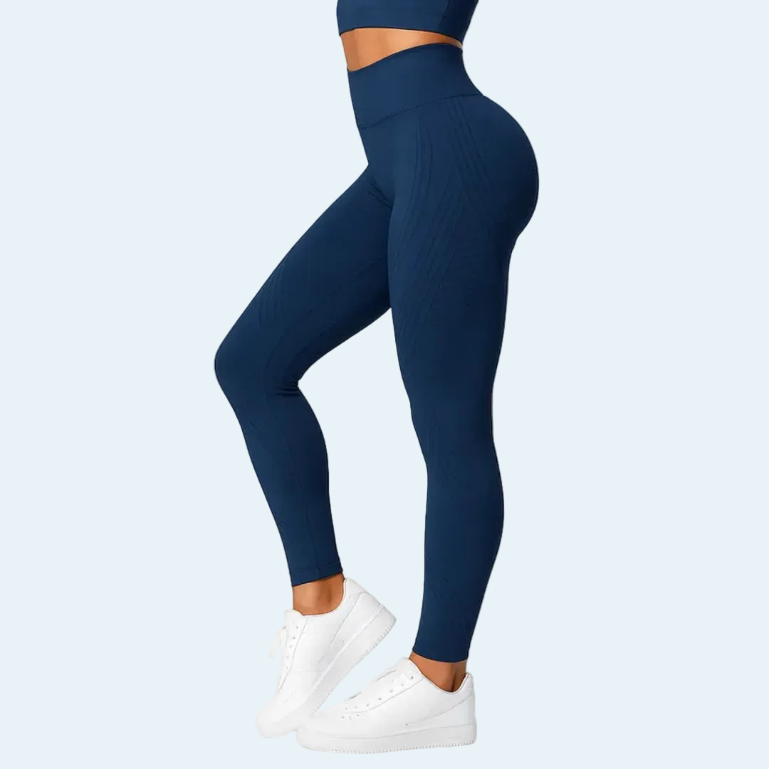 Donkerblauwe legging met hoge taille in zijaanzicht, gedragen met bijpassende top en witte sneakers, met fijne verticale ribbels. 4