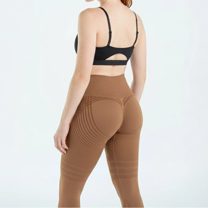 Achteraanzicht van een bruine legging met hoge tailleband en gebogen lijnen over de billen, gedragen met zwarte sporttop. 8