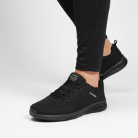 Zwarte gebreide sneaker gedragen met zwarte legging tegen een lichte achtergrond, zijaanzicht 6