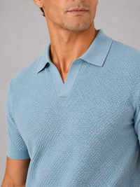 Close-up van de V-hals, kraag en structuurbreisel van het lichtblauwe poloshirt aan de borst 2