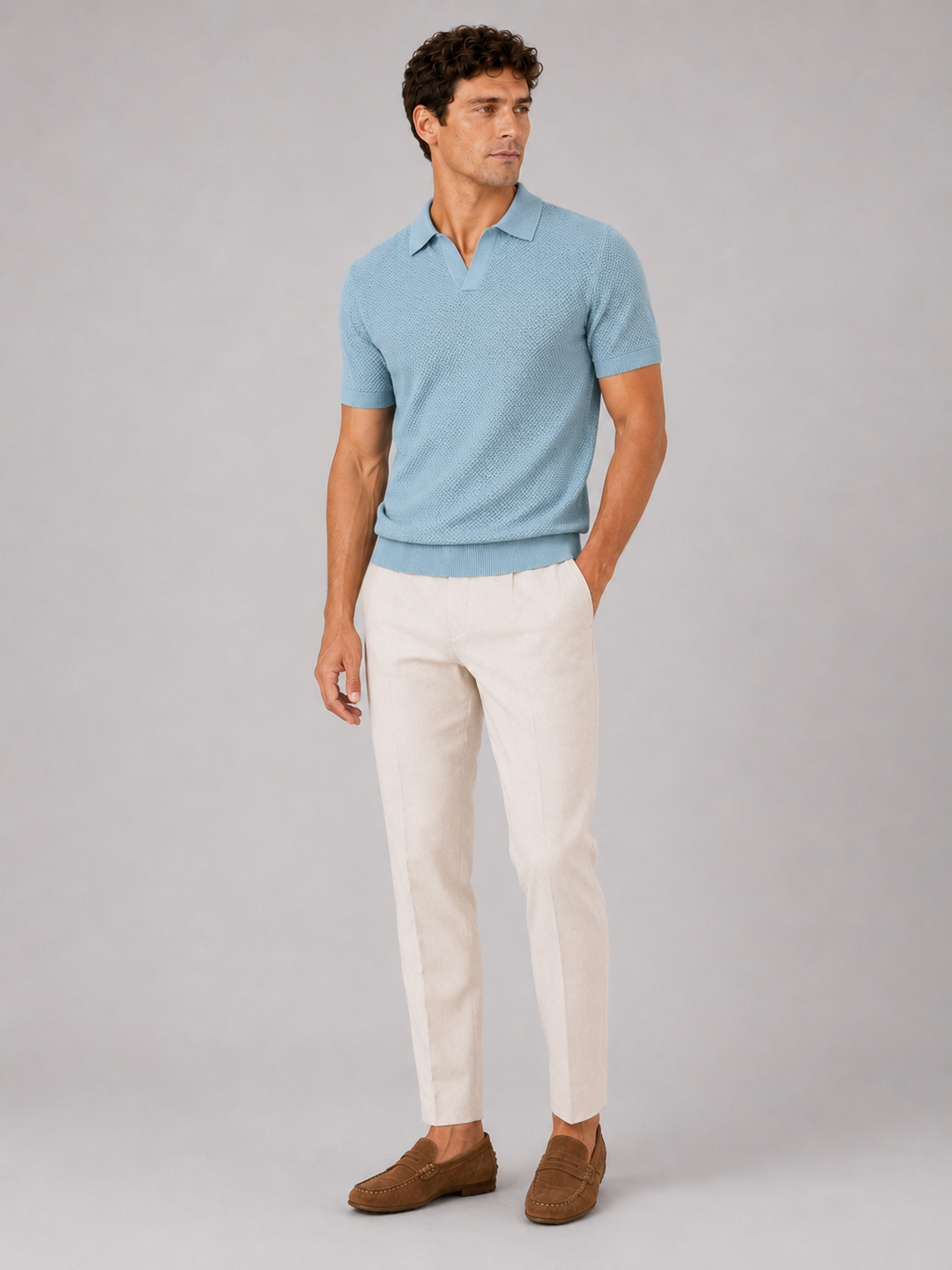 Lichtblauw gebreid poloshirt in volledig model van voren, gedragen met crèmekleurige broek en bruine suède loafers 3