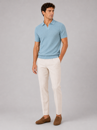Lichtblauw gebreid poloshirt in volledig model van voren, gedragen met crèmekleurige broek en bruine suède loafers 3