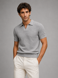 Man in grijs gebreid poloshirt met V-hals en crèmewitte broek, handen in zakken 26