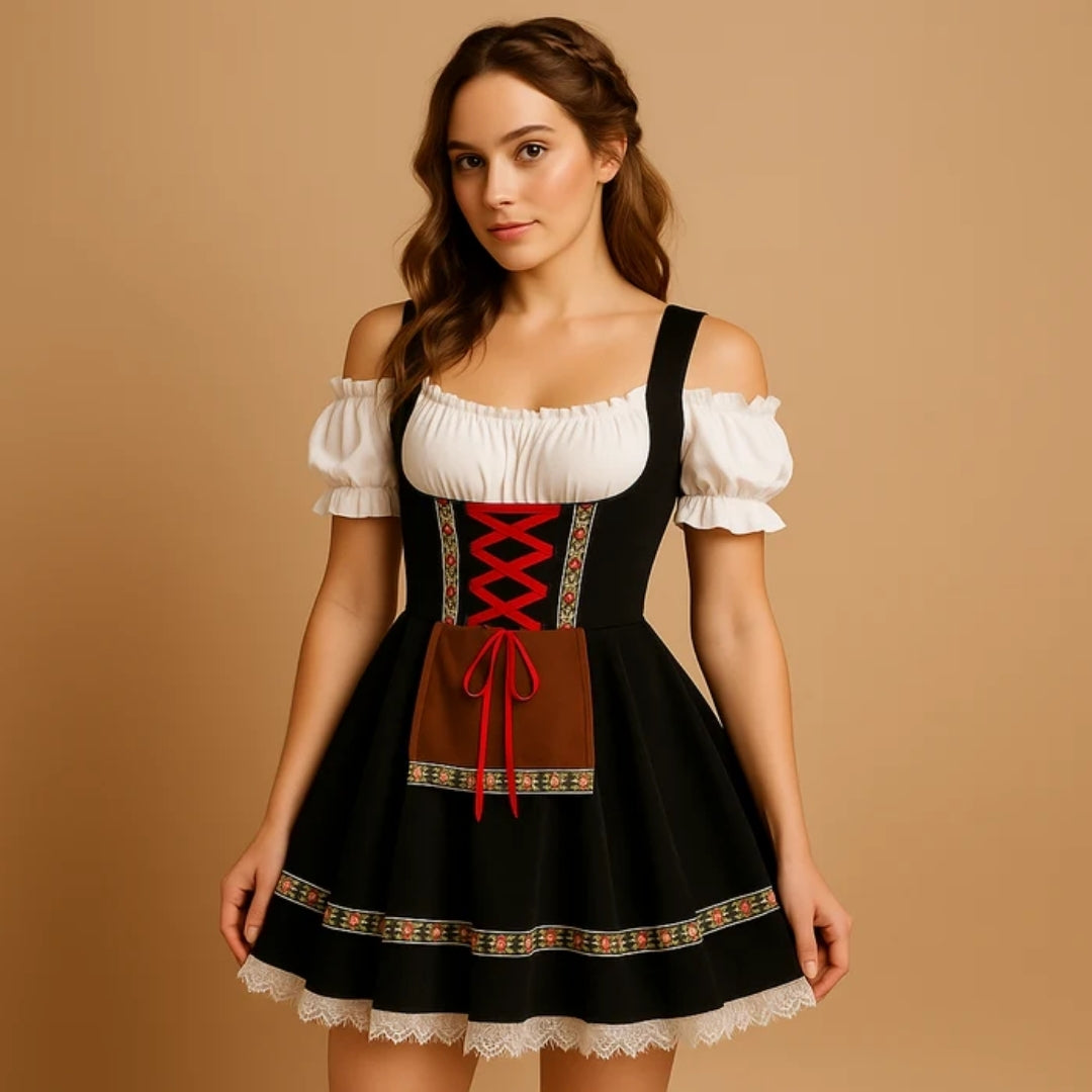 Model draagt een zwarte dirndl met rode kruisveters, bruin schortje, bloemenband langs de zoom en een witte kanten rand. 7