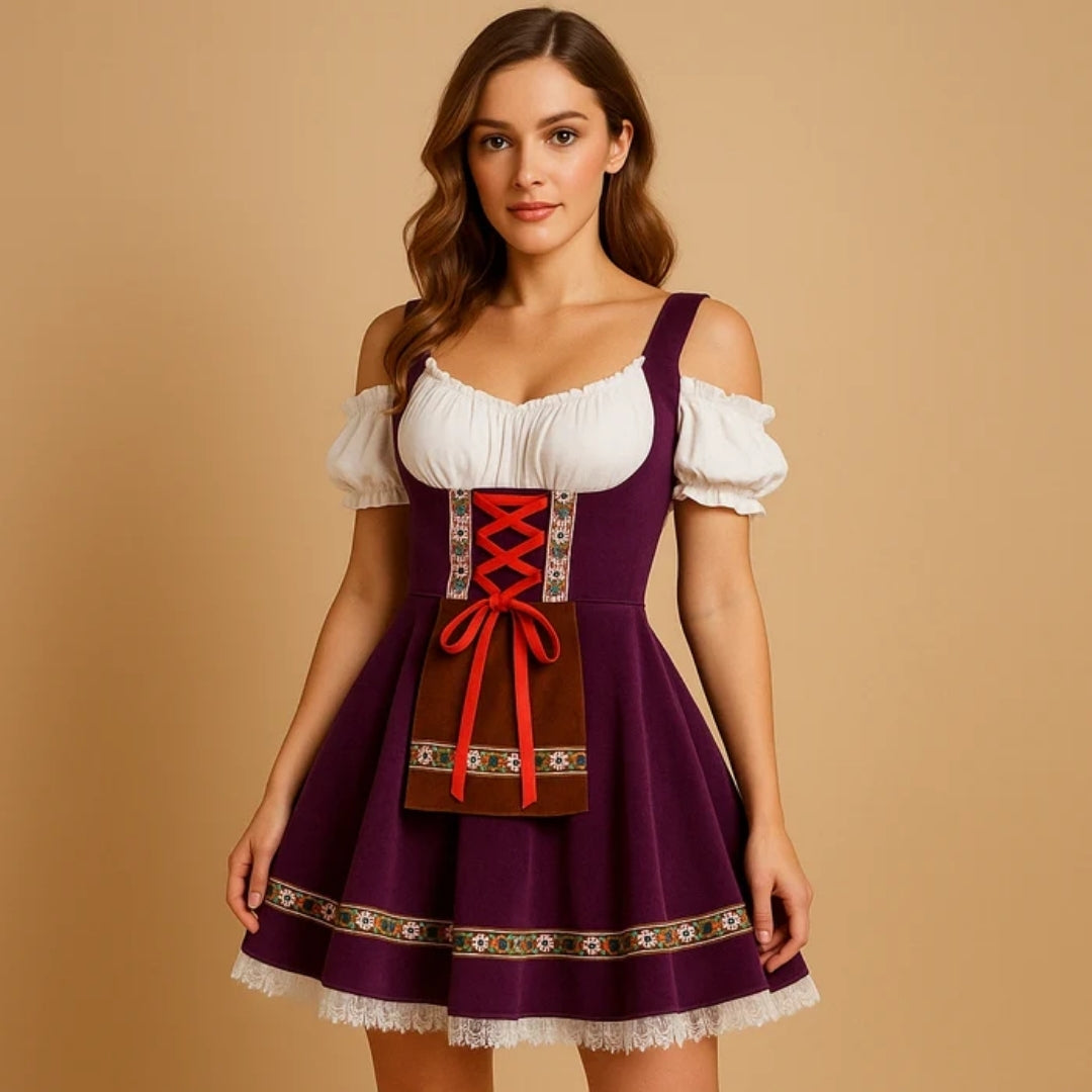 Model draagt een paarse dirndl met bruin schortje, rode strikveters, bloemenband langs de zoom en een kanten onderrok. 2